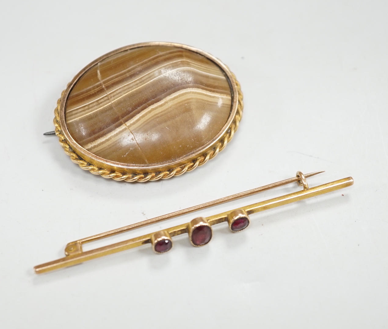 An early 20th century yellow metal and three stone garnet? set bar brooch, 72mm and one other brooch.